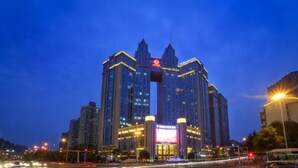 A multi-story building with a prominent entrance and illuminated signage, surrounded by a busy urban street at dusk. - Changsha Jiaxing Inn (Changsha)