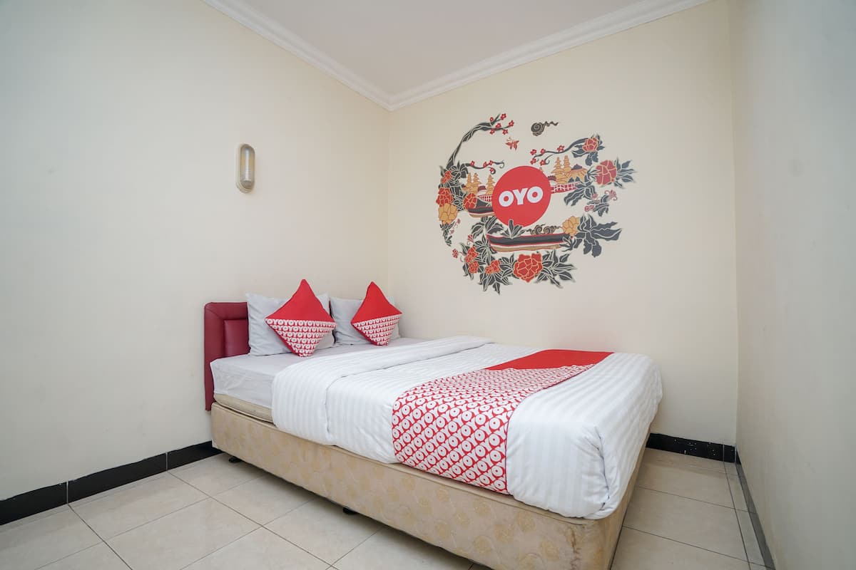 A bedroom with a bed, pillows, and a wall decoration.