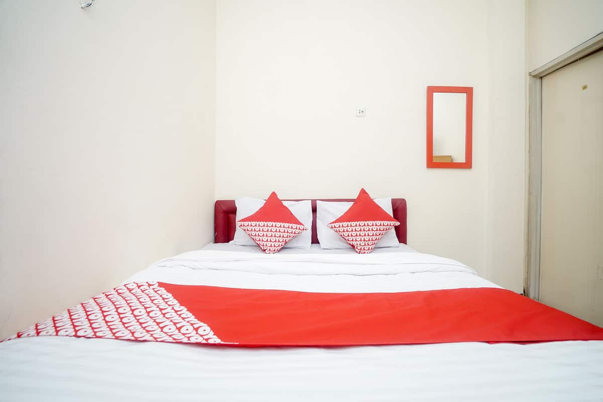 A bed with a red and white bedspread, two red pillows, and a red headboard.