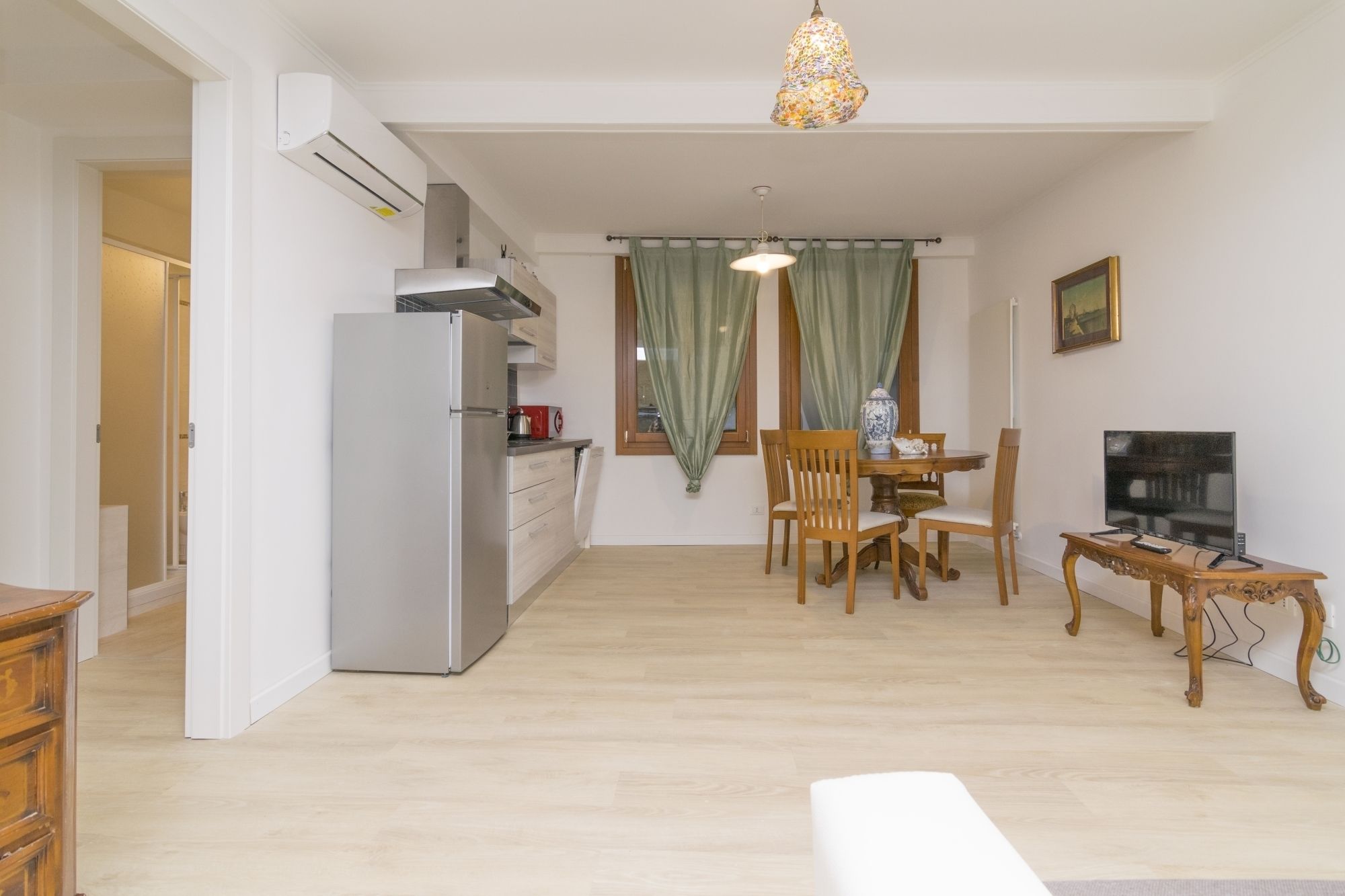 A compact living space with a kitchenette, dining area, and a TV.