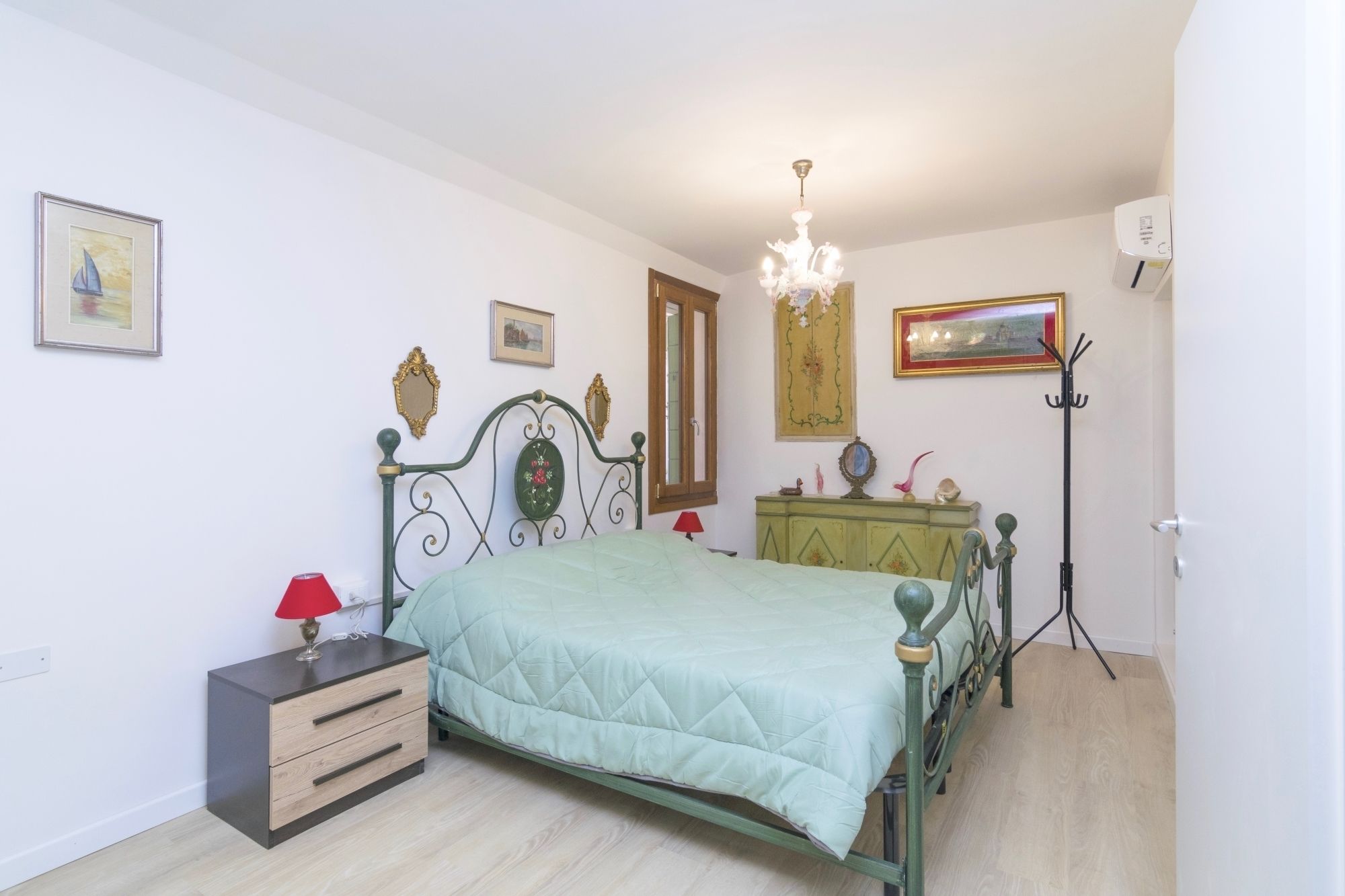 Quarto com cama, cômoda e lustre.