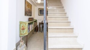 A staircase with a handrail, a green bookshelf with books, and two paintings on the wall. - Ca' Alberto Apartments 2 (Venice)