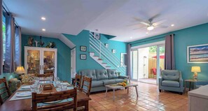 A spacious living room with a dining area, a staircase, and a view of the outdoors.