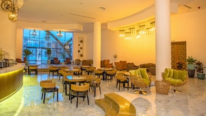 A spacious lobby with a marble floor, multiple seating areas including wicker chairs and sofas, and a large window offering a view of the outside. - Zina Beach Resort & SPA (Abdelmalek Ramdane)
