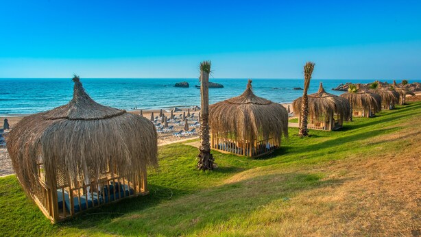 A row of thatched-roof huts with a view of the beach and ocean. - Zina Beach Resort & SPA (Abdelmalek Ramdane)