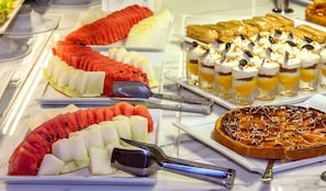 A buffet with various food items including watermelon, fruit, desserts, and a pie. - Zina Beach Resort & SPA (Abdelmalek Ramdane)