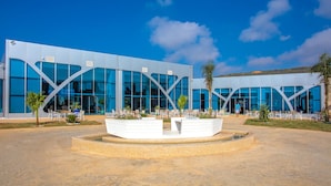 A modern building with large glass windows and a central courtyard with a water feature. - Zina Beach Resort & SPA (Abdelmalek Ramdane)