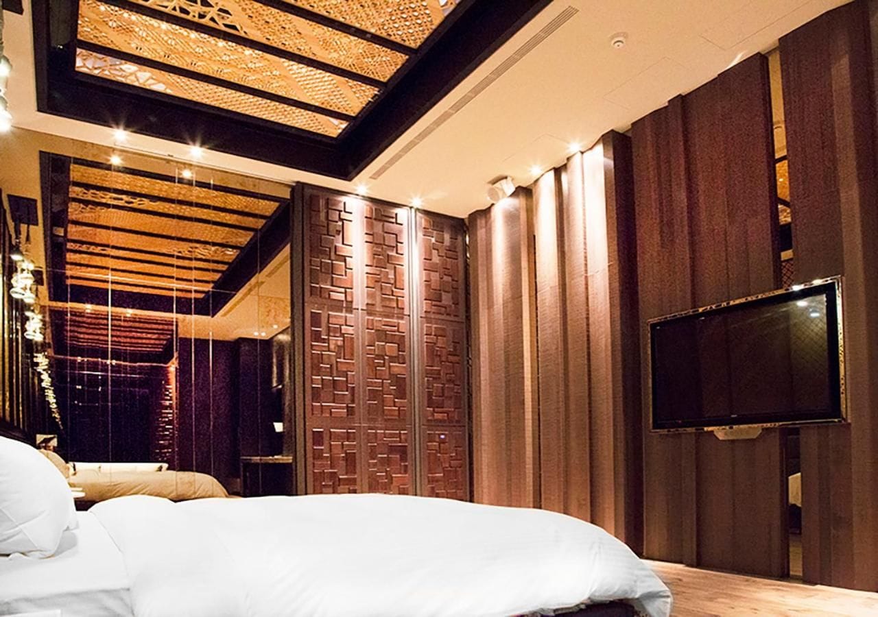 Un dormitorio moderno con una cama grande, un televisor montado en la pared y un diseño de pared de madera original.