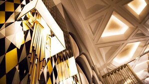 A geometric patterned wall and a modern chandelier in a hotel lobby.