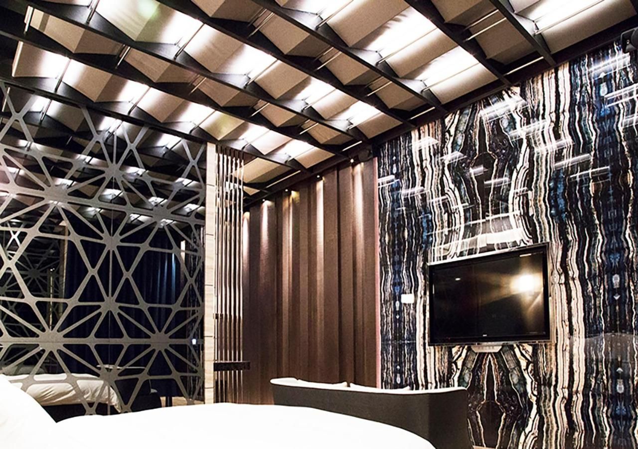 A modern interior with a geometric ceiling design, a curved white counter, and a wall-mounted television.