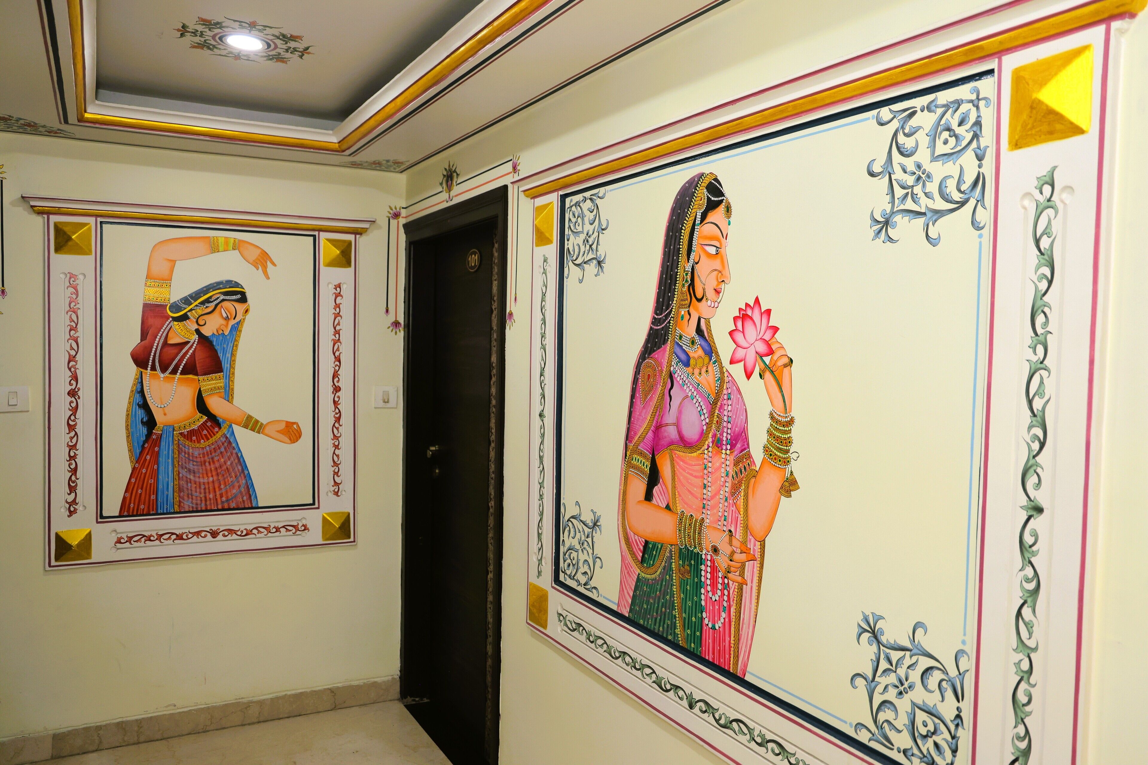 A hallway with two framed paintings of women in traditional attire.