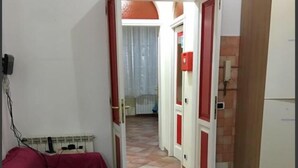 Ein Zimmer mit einem roten Bett, einem Fliesenboden und einer Tür zu einem anderen Raum.