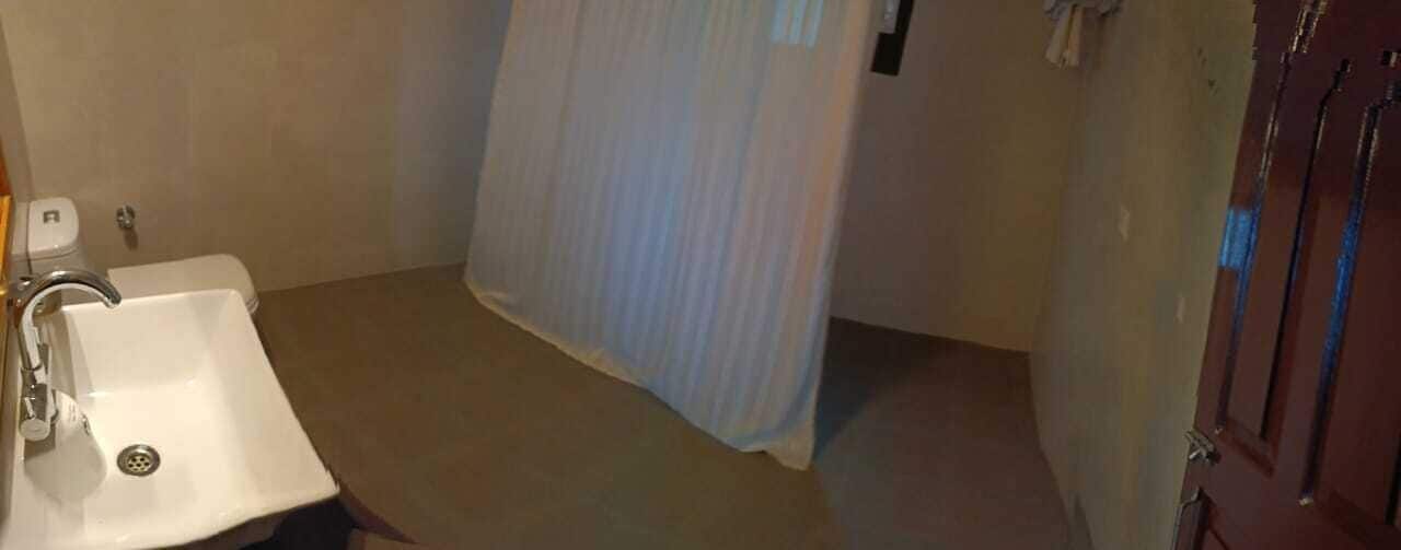 A bathroom with a sink, shower curtain, and a door.