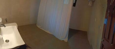 A bathroom with a sink, shower curtain, and a door.