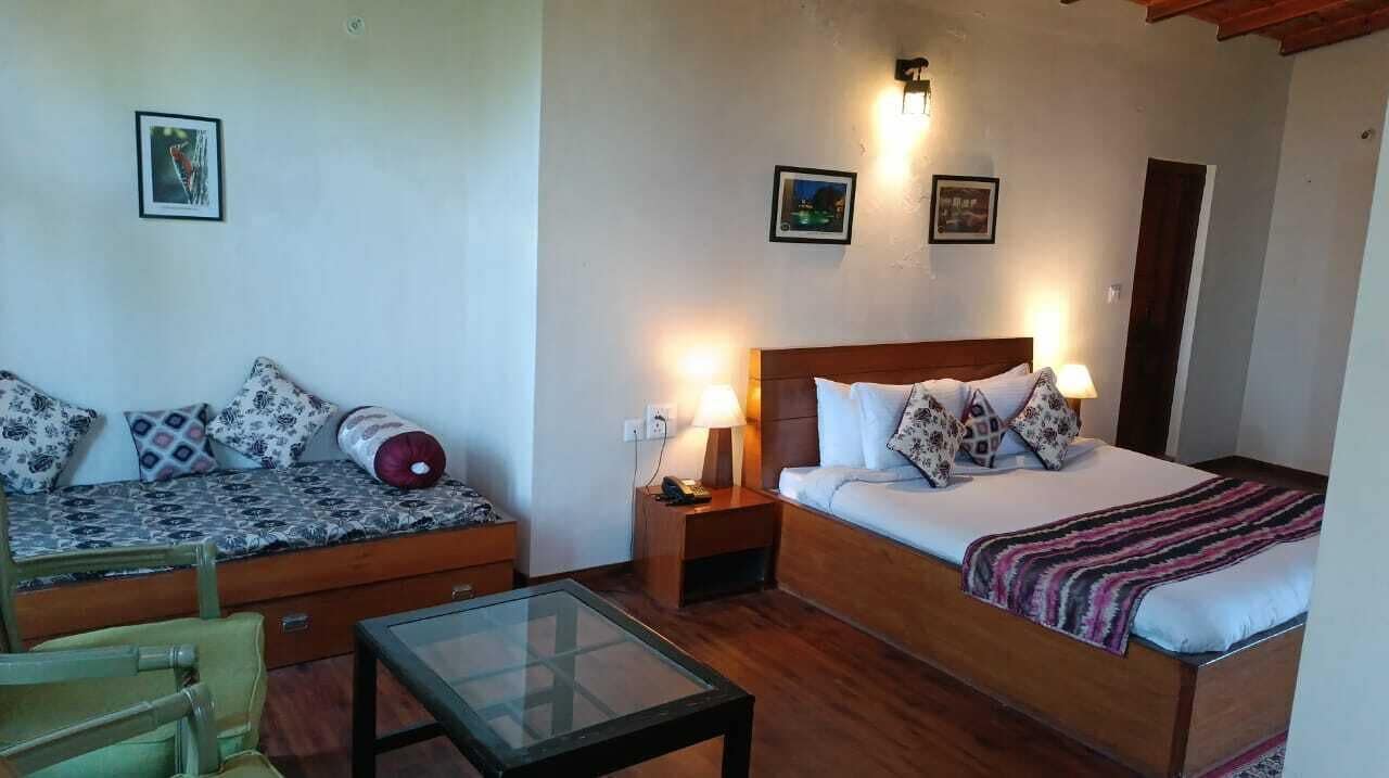 Ein gemütliches Zimmer mit einem Bett, einer Couch, einem Glastisch und zwei Nachttischlampen.