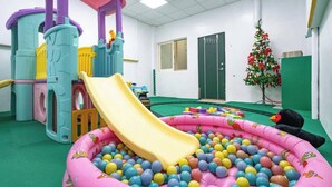 Zona de juegos con tobogán, piscina de pelotas y estructura inflable.