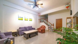 Una sala de estar con sofá, sillón, mesa de centro y una escalera que sube a otro nivel.