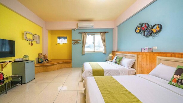 Habitación de hotel con dos camas, televisión, refrigerador y ventana con cortinas.