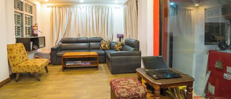 Una sala de estar con sofá, sillón, mesa de centro y un ordenador portátil sobre una mesita auxiliar.
