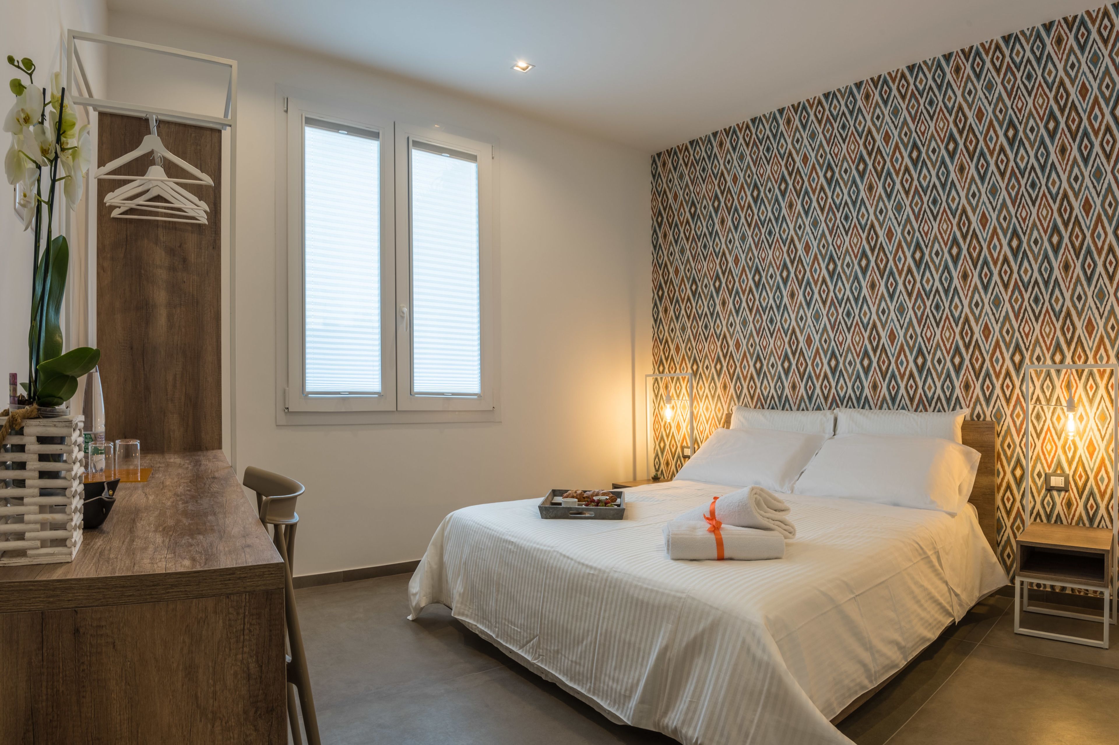 A bedroom with a bed, bedside table, and a dresser with a mirror.