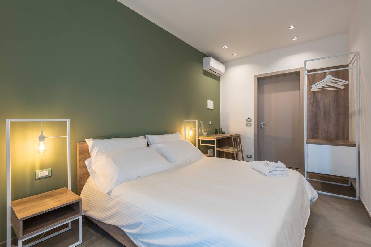 A modern bedroom with a bed, bedside table, and a wardrobe.