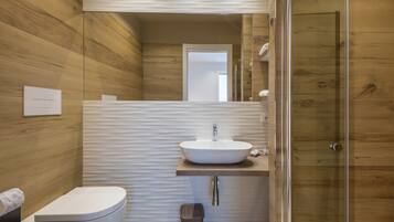 A modern bathroom with a wooden wall, a white sink, and a glass shower enclosure.