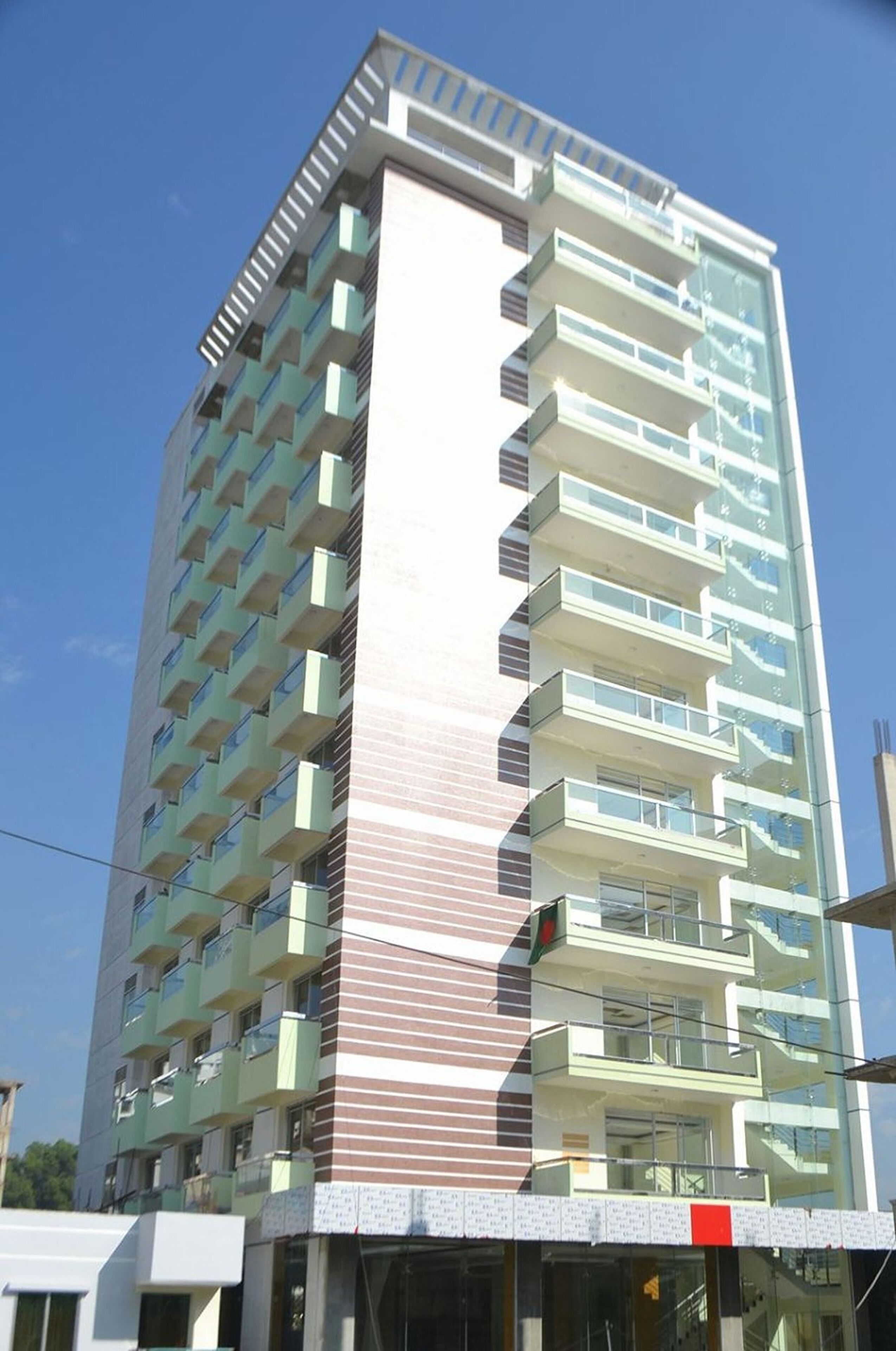 Un edificio de varios pisos con un diseño arquitectónico moderno, que presenta balcones en cada planta.