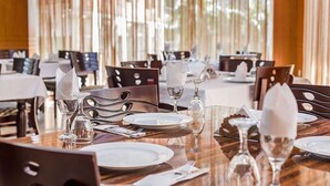 A restaurant with round tables set for dining, featuring white plates, silverware, and clear glassware.