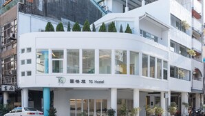 A modern building with a white facade, large windows, and a sign indicating it is a TG Hostel. - TG Hostel (Taichung)