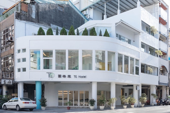 A modern building with a white facade, large windows, and a sign indicating it is a TG Hostel. - TG Hostel (Taichung)