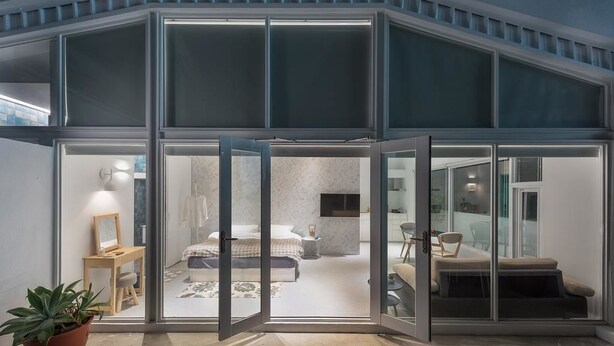 A modern bedroom with a large bed, a bedside table, and a TV. - TG Hostel (Taichung)