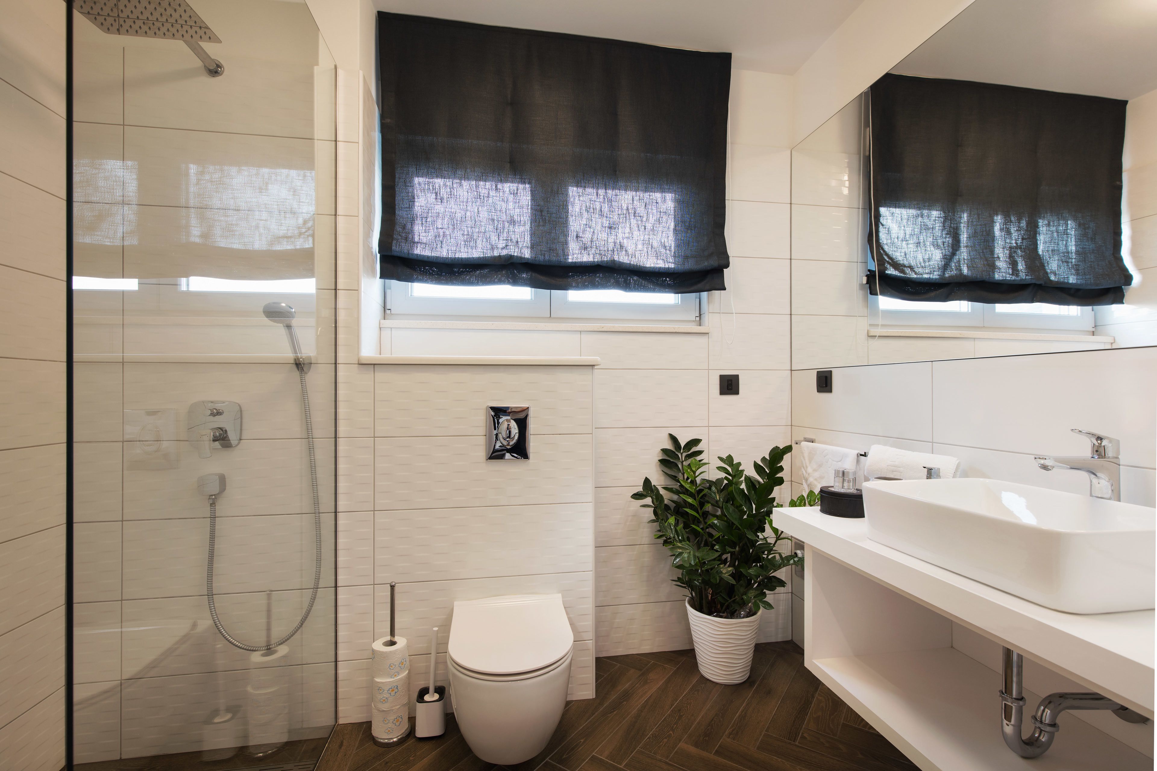 Un baño moderno con ducha, inodoro, lavamanos y una planta en maceta.