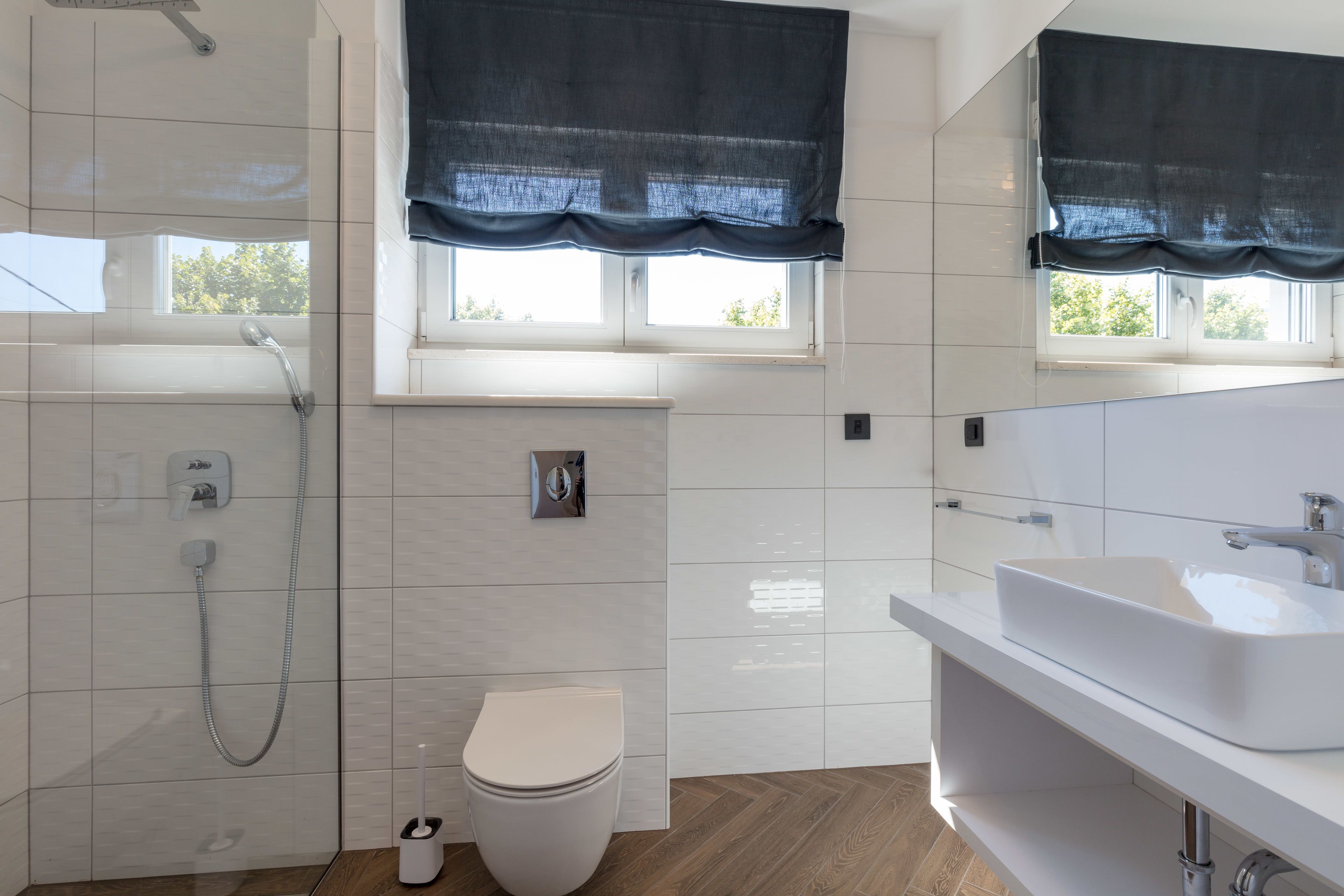 A modern bathroom with a shower, toilet, and sink.