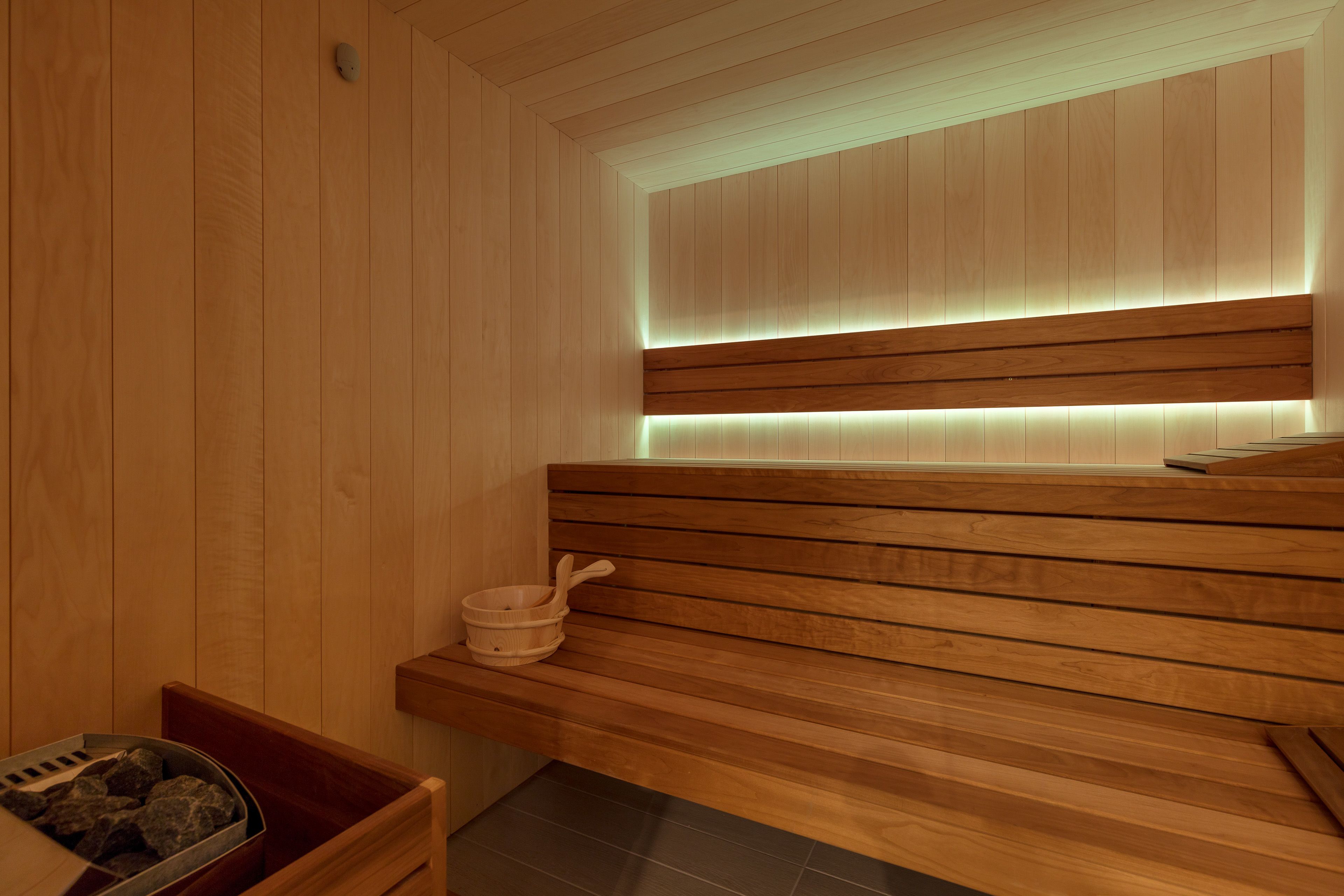 Uma sauna de madeira com um banco e uma pequena bacia de madeira.