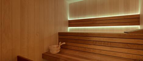 Uma sauna de madeira com um banco e uma pequena bacia de madeira.