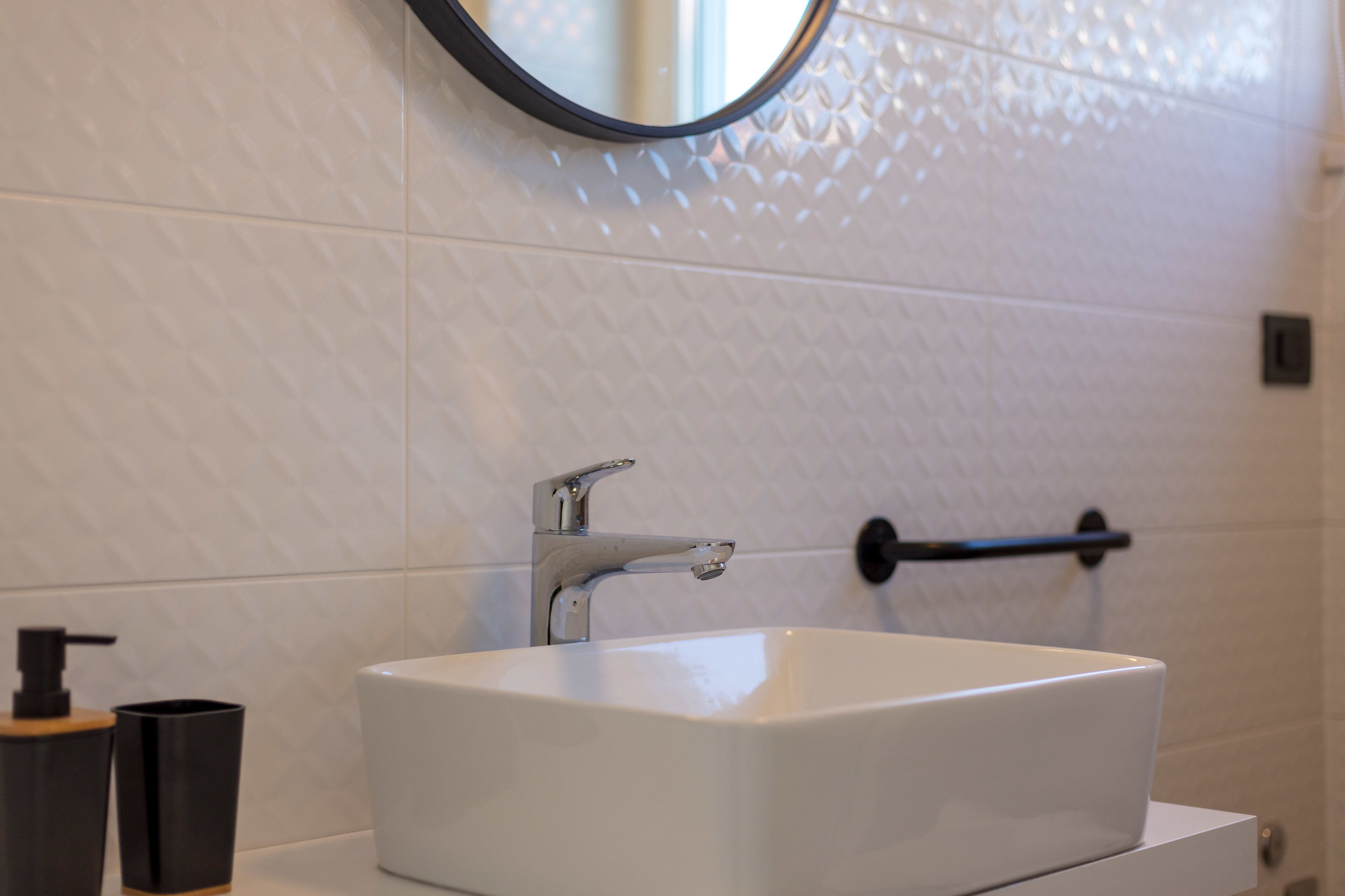 Une salle de bain avec un lavabo blanc, un miroir et un porte-serviettes.