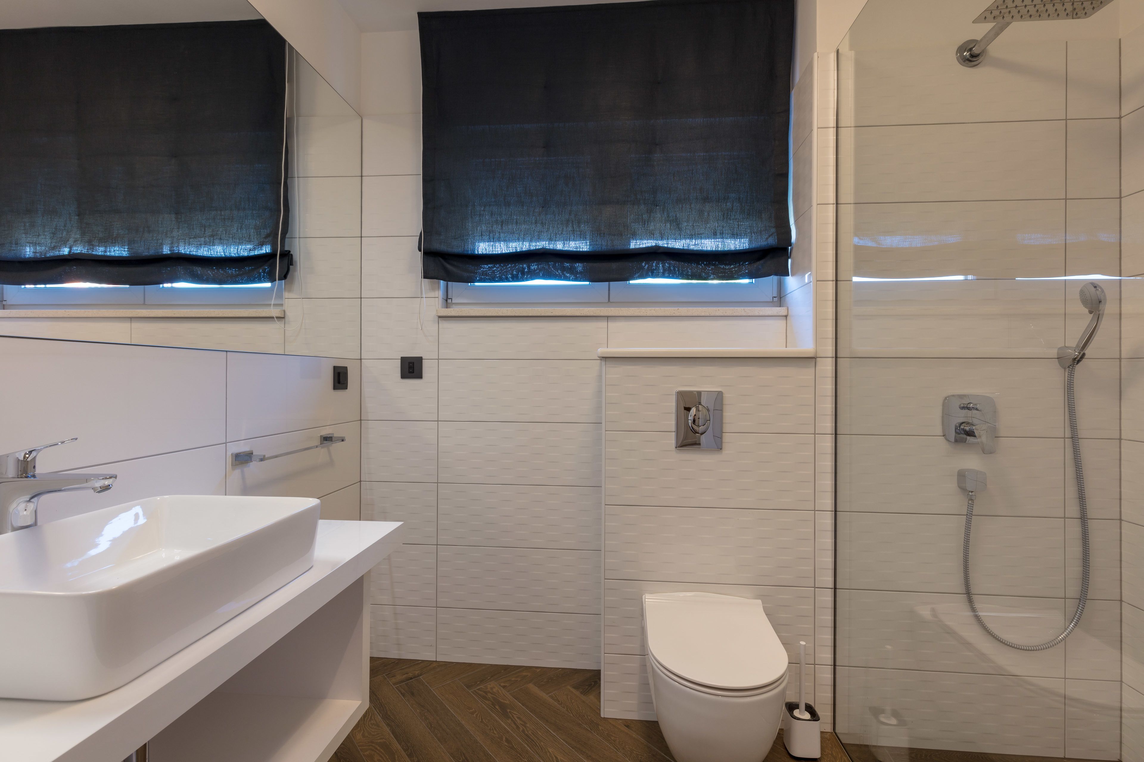 Ein modernes Badezimmer mit Waschbecken, Toilette und Dusche, alles in Weiß.