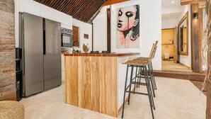 A modern kitchen with a wooden island, stainless steel appliances, and a large painting on the wall. - La Cabane Bali (Jimbaran)