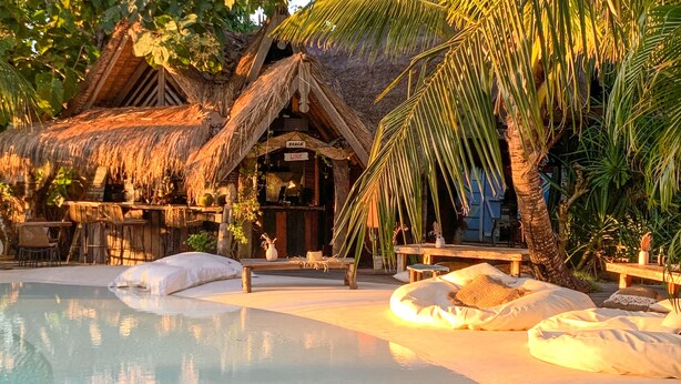 A poolside area with a thatched-roof structure, lounge chairs, and a bench. - La Cabane Bali (Jimbaran)
