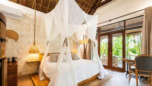 A bedroom with a four-poster bed, wooden flooring, a bedside table, a lamp, and a view of the outdoors. - La Cabane Bali (Jimbaran)