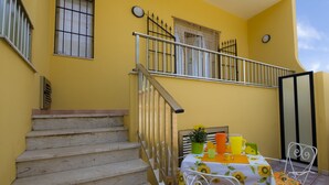 A yellow building with a staircase and a table set with a sunflower tablecloth. - Fiori Gialli Caucana (Santa Croce Camerina)