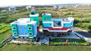 A multi-story building with a unique architectural design, featuring a mix of blue, white, and red colors. - Starrysky Family (Magong)