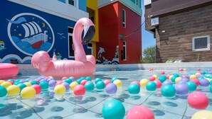 A swimming pool with colorful balls and a large pink flamingo float. - Starrysky Family (Magong)