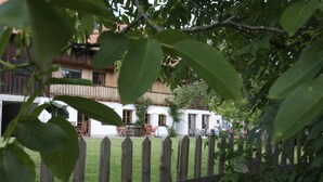 A wooden fence with a grassy yard and a building with a balcony in the background.