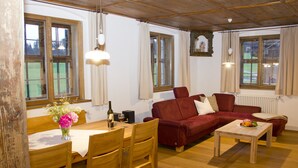 A cozy living room with a wooden dining table, red sofa, and a wooden coffee table.