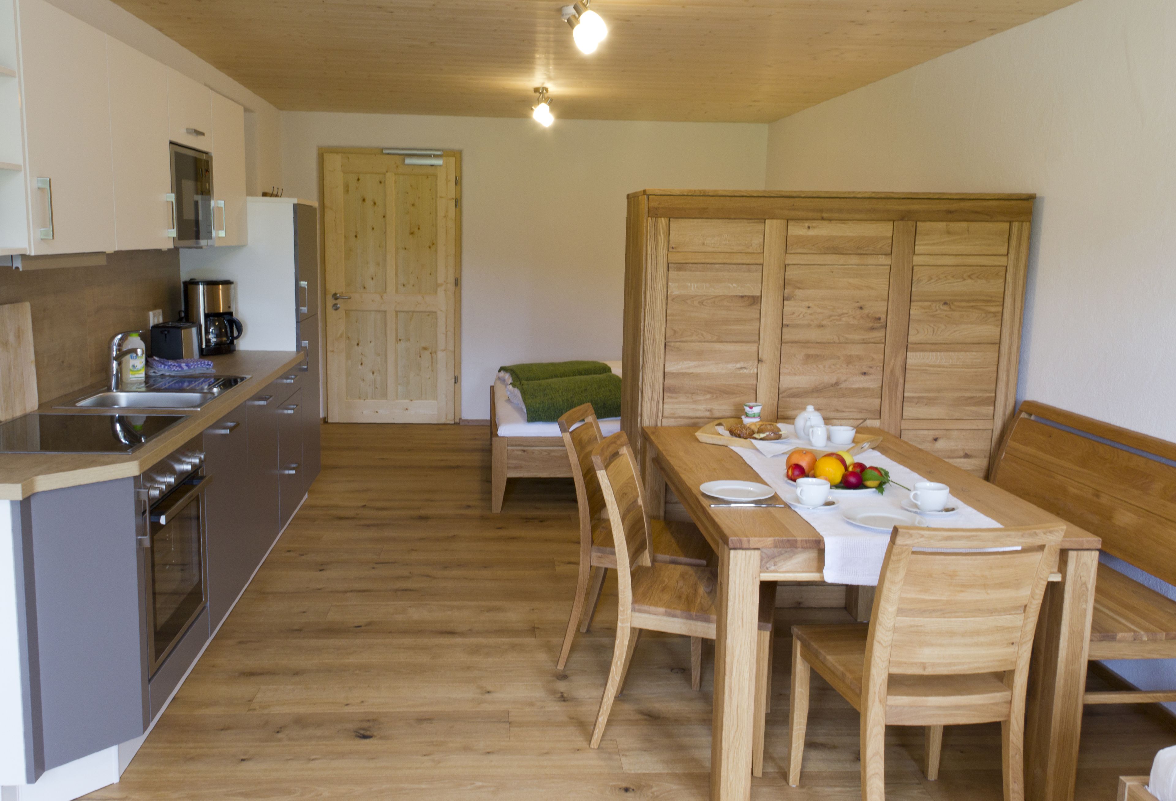 Eine moderne Küche mit Einbauofen und Essbereich, ausgestattet mit Holzmöbeln und einem Tisch für zwei Personen.