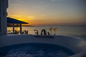 A hot tub with two glasses of wine, overlooking a sunset over the ocean. - Villa Kanutan (Motobu)
