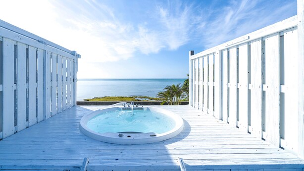 A wooden deck with a hot tub and a view of the ocean. - Villa Kanutan (Motobu)