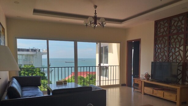 A spacious living room with a large window offering a view of the sea and a balcony. - Seaview Winner Pool Villa (Ho Chi Minh City)