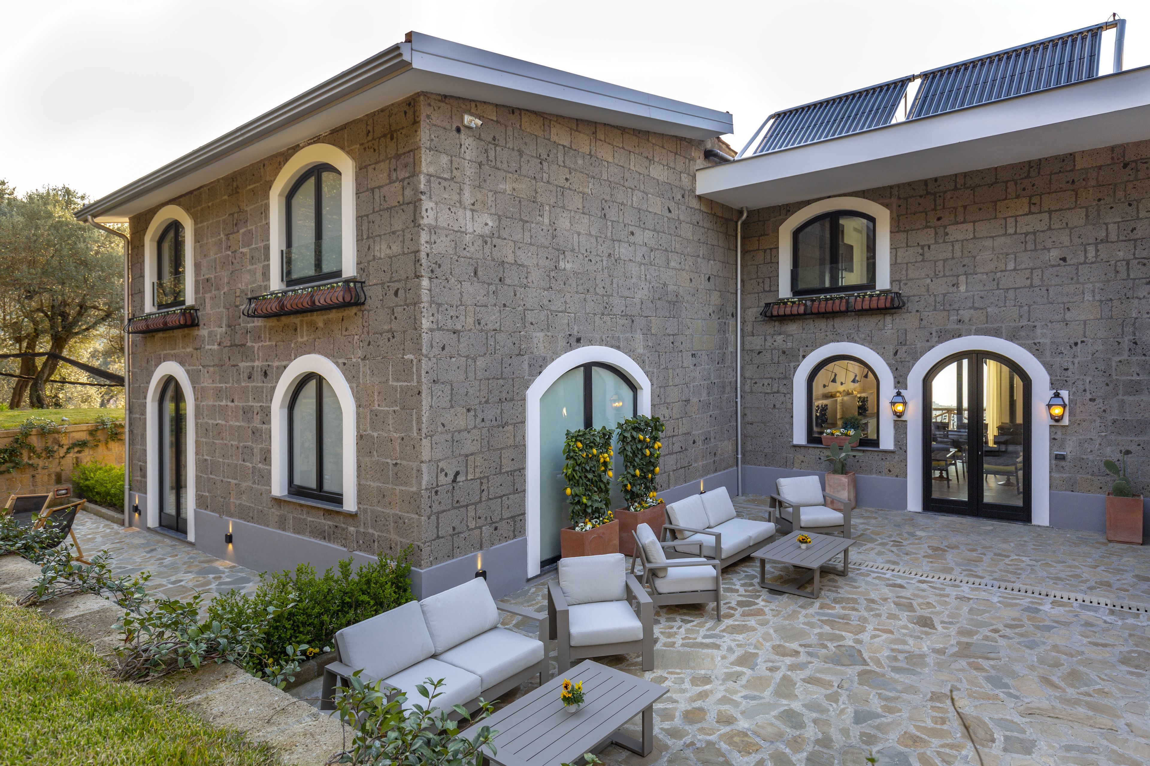 A stone building with a patio area featuring outdoor furniture and potted plants.